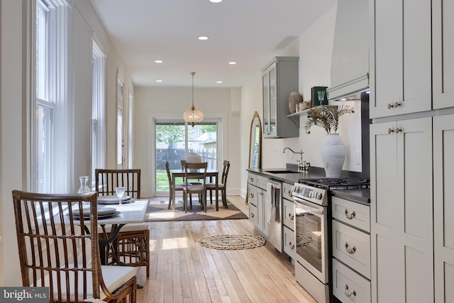 kitchen featuring recessed lighting, decorative light fixtures, light wood-style floors, appliances with stainless steel finishes, and dark countertops