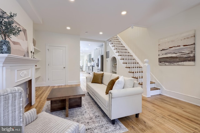 living area with baseboards, stairway, wood finished floors, and recessed lighting