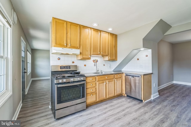 kitchen with appliances with stainless steel finishes, baseboards, and under cabinet range hood