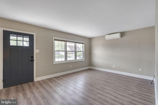 entrance foyer featuring baseboards, wood finished floors, and an AC wall unit