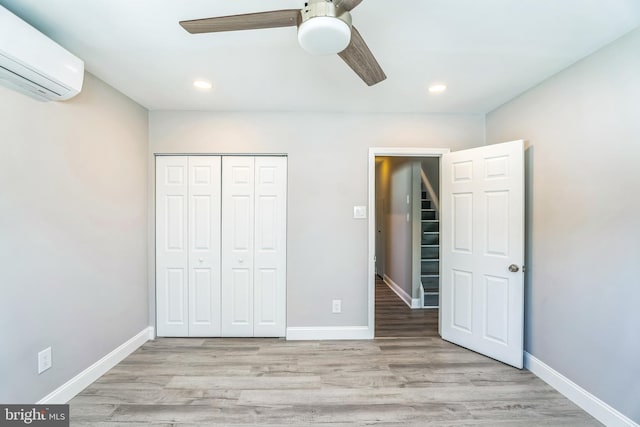 unfurnished bedroom featuring recessed lighting, light wood-style flooring, a closet, and a wall mounted AC