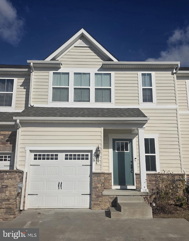 view of front facade featuring stone siding, driveway, and a garage