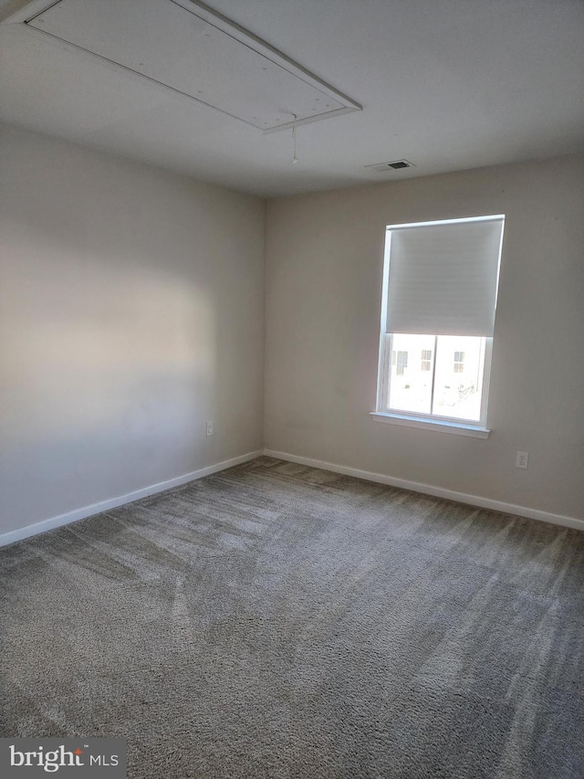 carpeted empty room featuring attic access, baseboards, and visible vents