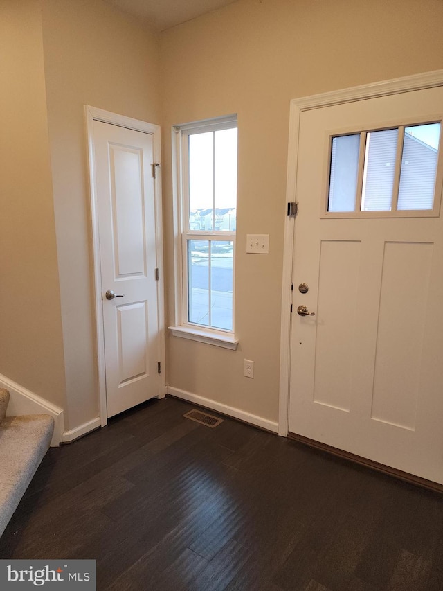 foyer with baseboards, visible vents, dark wood-style floors, and stairway