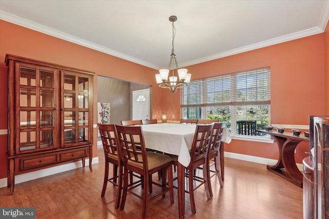 dining room with wood finished floors, a chandelier, crown molding, and baseboards
