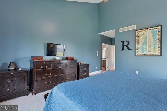 bedroom with visible vents, light colored carpet, and a towering ceiling
