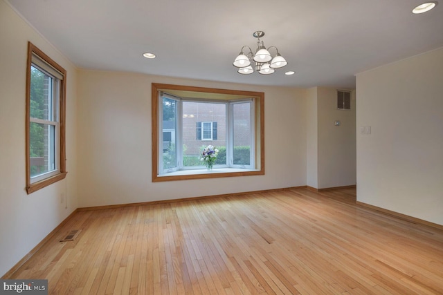 empty room featuring light wood-style floors, a chandelier, baseboards, and recessed lighting