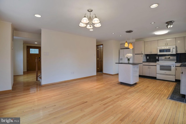 kitchen with white appliances, light wood-type flooring, dark countertops, decorative backsplash, and a center island