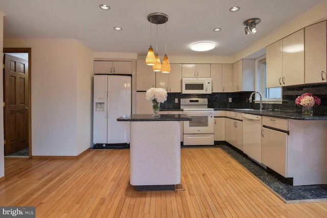 kitchen with white appliances, a sink, light wood-type flooring, decorative backsplash, and a center island