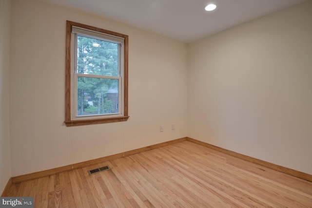 empty room with plenty of natural light, wood finished floors, baseboards, and recessed lighting