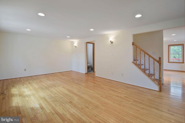 unfurnished living room with light wood-style floors, recessed lighting, stairway, and baseboards
