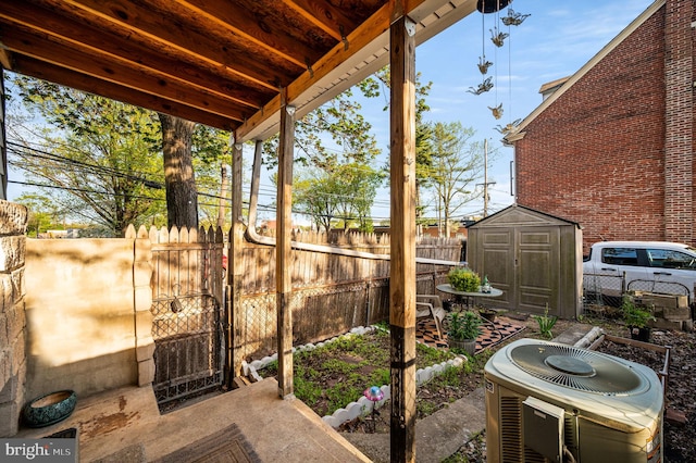 view of patio / terrace with an outdoor structure, central AC, fence, and a shed
