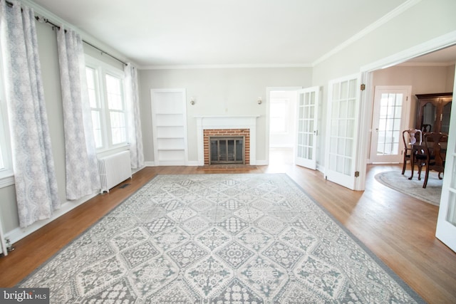 23075 Hollywood Rd, Leonardtown, MD 20650 - living area featuring radiator heating unit, wood finished floors, a fireplace, baseboards, and ornamental molding
