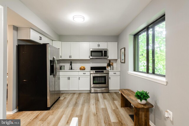 7374 Hickory Log Cir, Columbia, MD 21045 - kitchen featuring stainless steel appliances, white cabinetry, light wood finished floors, light countertops, and a sink