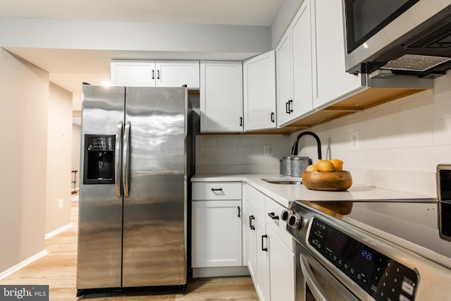 7374 Hickory Log Cir, Columbia, MD 21045 - kitchen featuring appliances with stainless steel finishes, a sink, backsplash, white cabinets, and light wood-style flooring