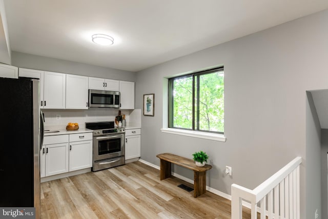 7374 Hickory Log Cir, Columbia, MD 21045 - kitchen with appliances with stainless steel finishes, light countertops, white cabinets, and light wood-style flooring