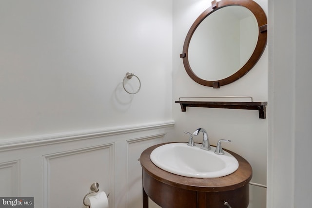 bathroom featuring a decorative wall, wainscoting, and a sink