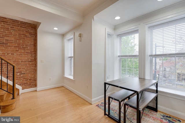 unfurnished dining area featuring ornamental molding, baseboards, light wood-type flooring, and stairway