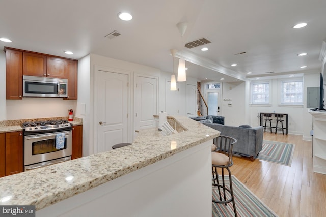 kitchen featuring stainless steel appliances, visible vents, a kitchen bar, and brown cabinets