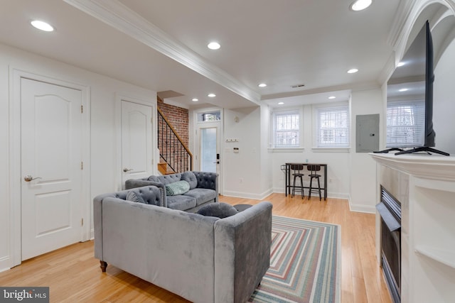 living room with recessed lighting, light wood-style floors, electric panel, crown molding, and stairs
