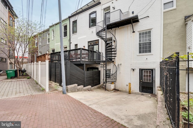 back of house featuring brick siding, a patio, stairway, and fence