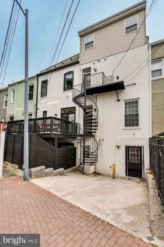 back of house featuring brick siding, stairway, fence, and a patio area