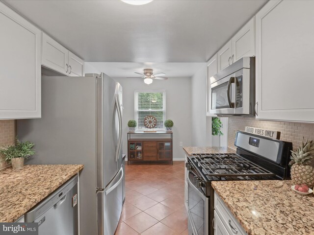 6558 Gildar St, Alexandria, VA 22310 - kitchen featuring stainless steel appliances, tasteful backsplash, light tile patterned floors, and white cabinetry