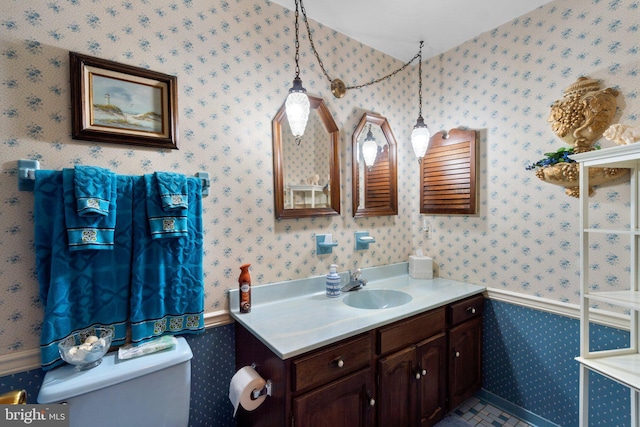bathroom with wallpapered walls, toilet, and vanity