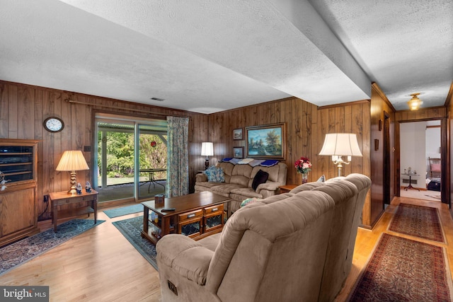 living room featuring wooden walls, a textured ceiling, and wood finished floors