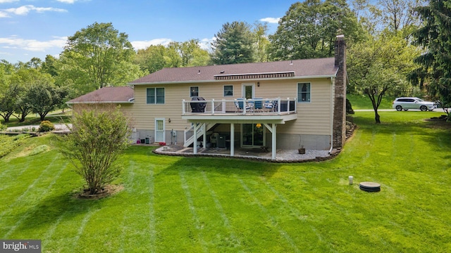 rear view of property featuring a deck, stairway, a chimney, and a lawn