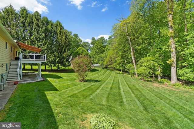 view of grassy yard featuring stairway and a wooden deck