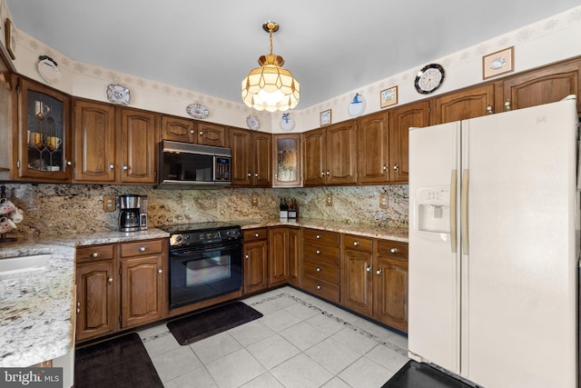 kitchen with black appliances, decorative backsplash, light tile patterned floors, glass insert cabinets, and pendant lighting