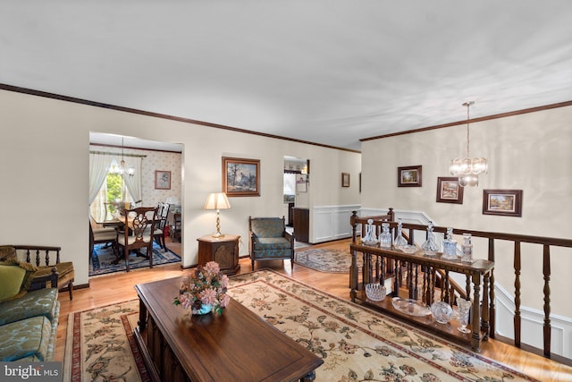 living area with a chandelier, light wood-style floors, and crown molding