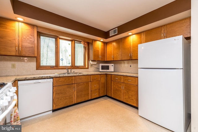 kitchen with brown cabinets, decorative backsplash, a sink, visible vents, and white appliances