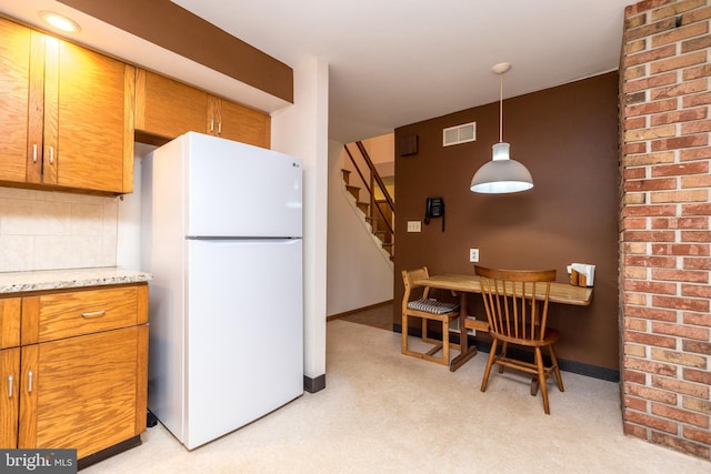 kitchen featuring light stone counters, decorative backsplash, light colored carpet, visible vents, and freestanding refrigerator