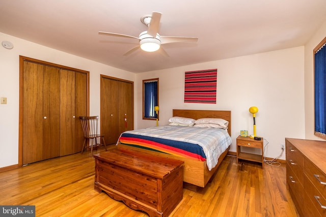 bedroom with baseboards, two closets, ceiling fan, and light wood-type flooring