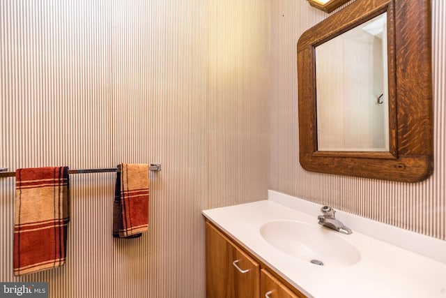 bathroom with wallpapered walls and vanity