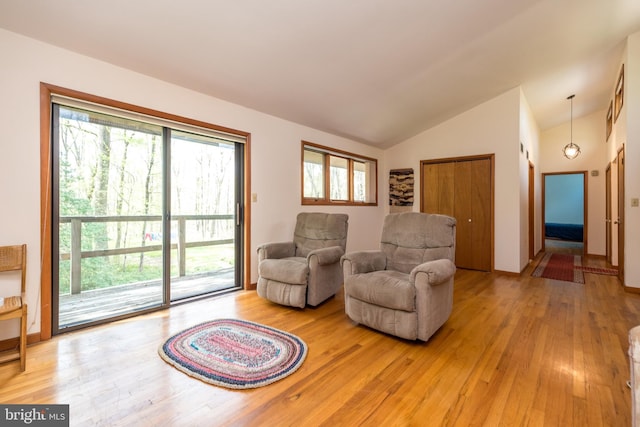 living area featuring light wood-type flooring, a healthy amount of sunlight, and lofted ceiling