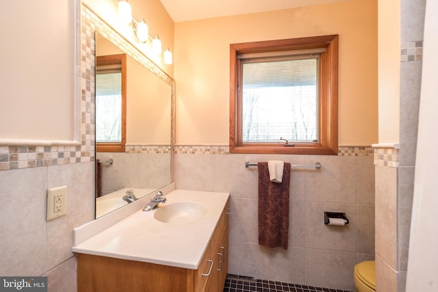 bathroom featuring a wealth of natural light, vanity, wainscoting, and tile walls