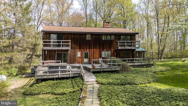 rear view of house featuring a chimney, central AC, a balcony, and a deck