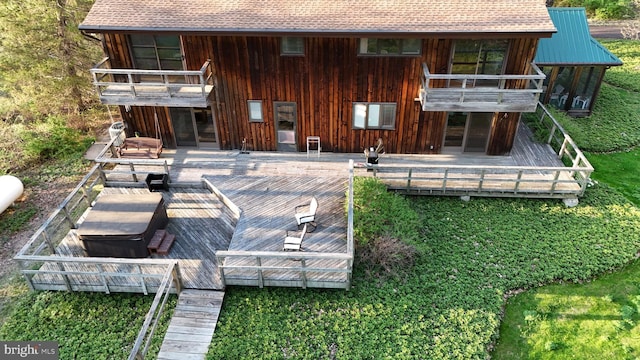 rear view of house with a balcony, roof with shingles, and a deck