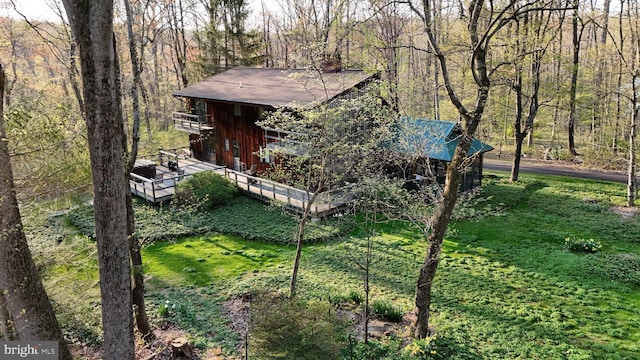 view of side of home with a lawn, a wooded view, and a deck
