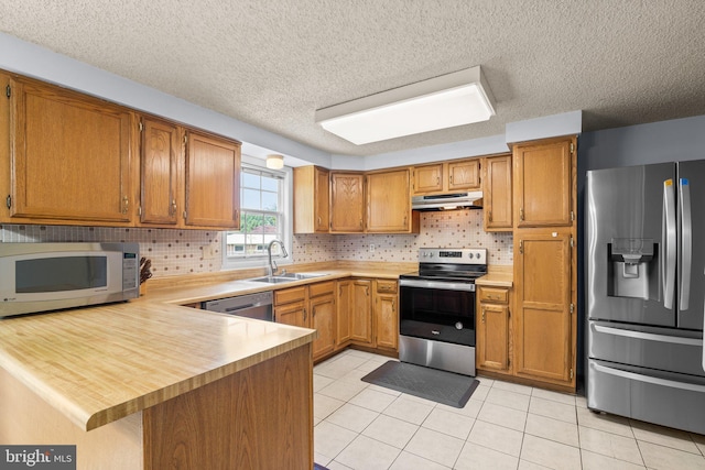 12916 New Hampshire Ave, Silver Spring, MD 20904 - kitchen with appliances with stainless steel finishes, under cabinet range hood, light countertops, a peninsula, and a textured ceiling