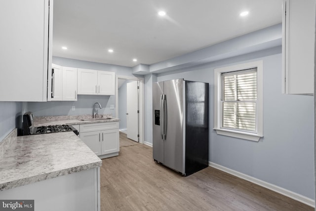 kitchen with white cabinets, stainless steel refrigerator with ice dispenser, gas range oven, and a sink