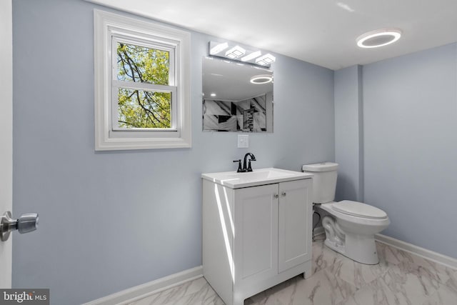 bathroom with marble finish floor, toilet, vanity, and baseboards