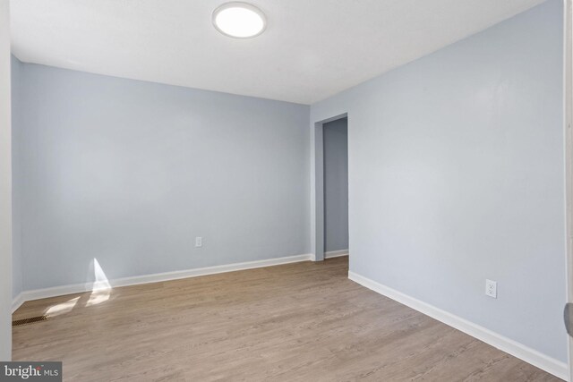 unfurnished room featuring baseboards and light wood-style flooring