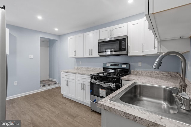 kitchen featuring white cabinets, light countertops, a sink, and appliances with stainless steel finishes