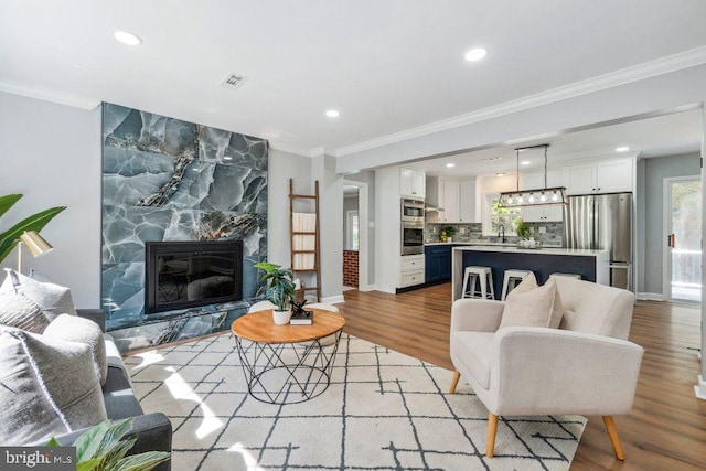living room with recessed lighting, visible vents, a large fireplace, and light wood finished floors