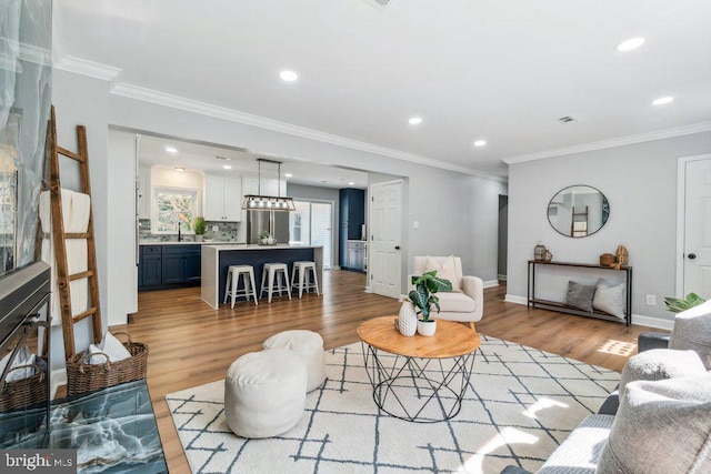 living room featuring light wood-type flooring, recessed lighting, baseboards, and ornamental molding