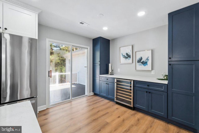 bar with light wood finished floors, freestanding refrigerator, recessed lighting, wine cooler, and visible vents